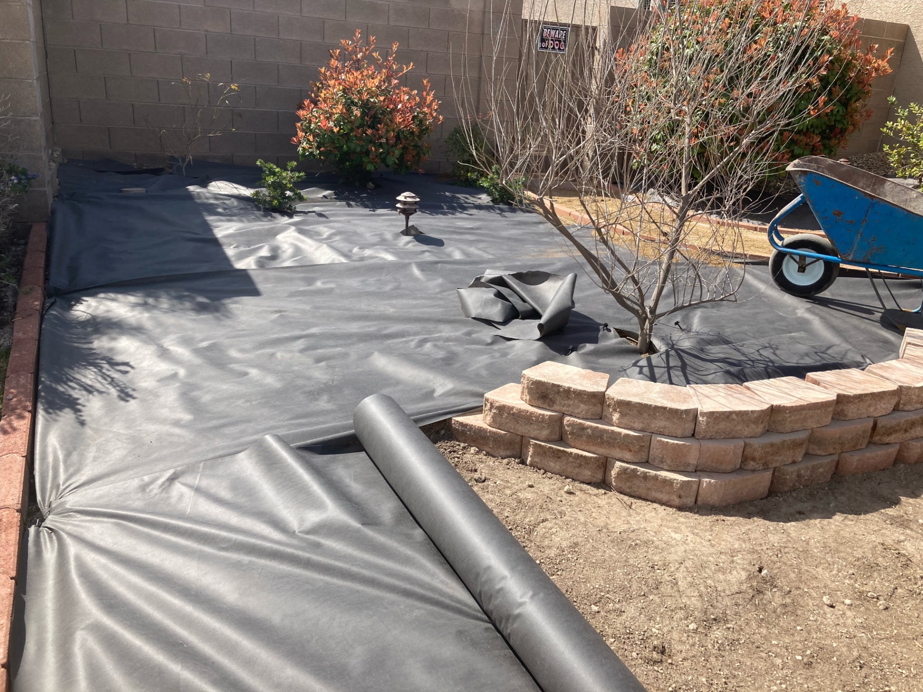 Xeriscape installation in progress with landscape fabric and stone borders