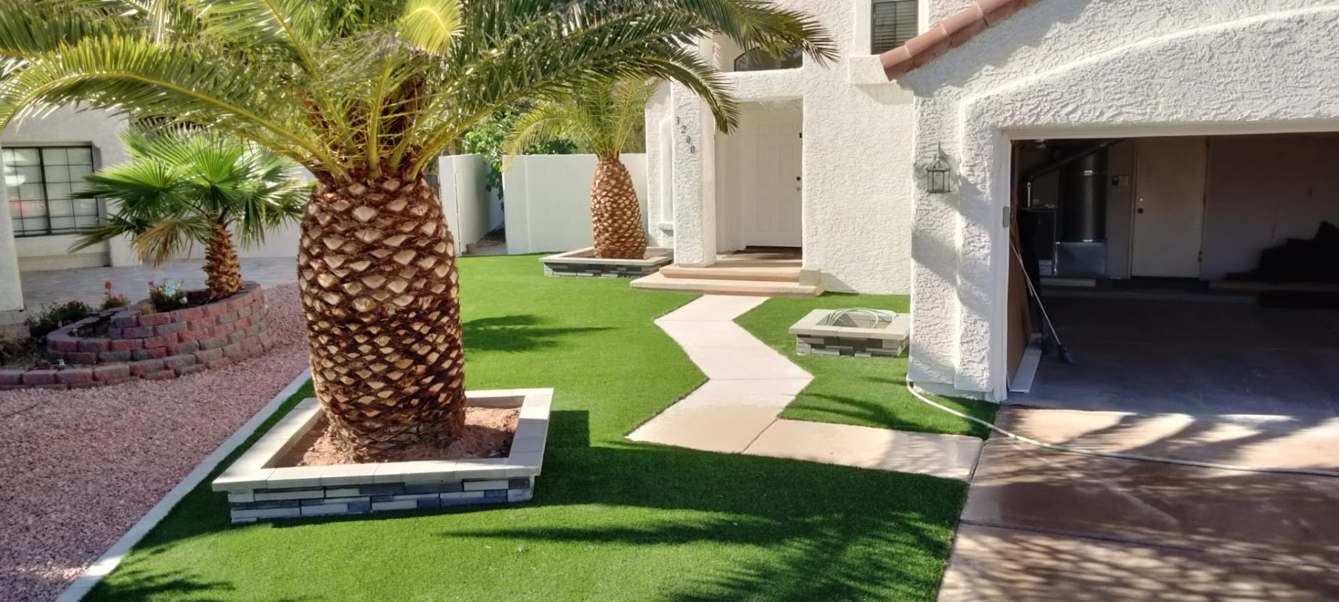 Front yard artificial turf installation with palms and walkway